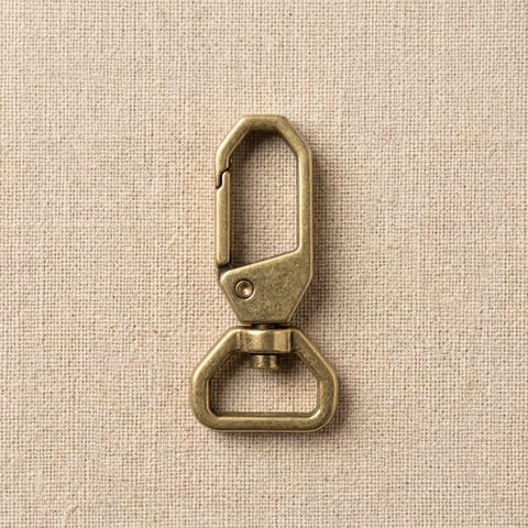 Antique brass octagonal swivel snap hook on linen