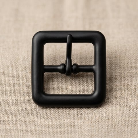 Compact matte black square footwear buckle on linen