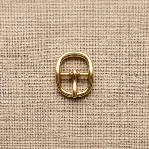 Polished brass compact oval footwear buckle on linen