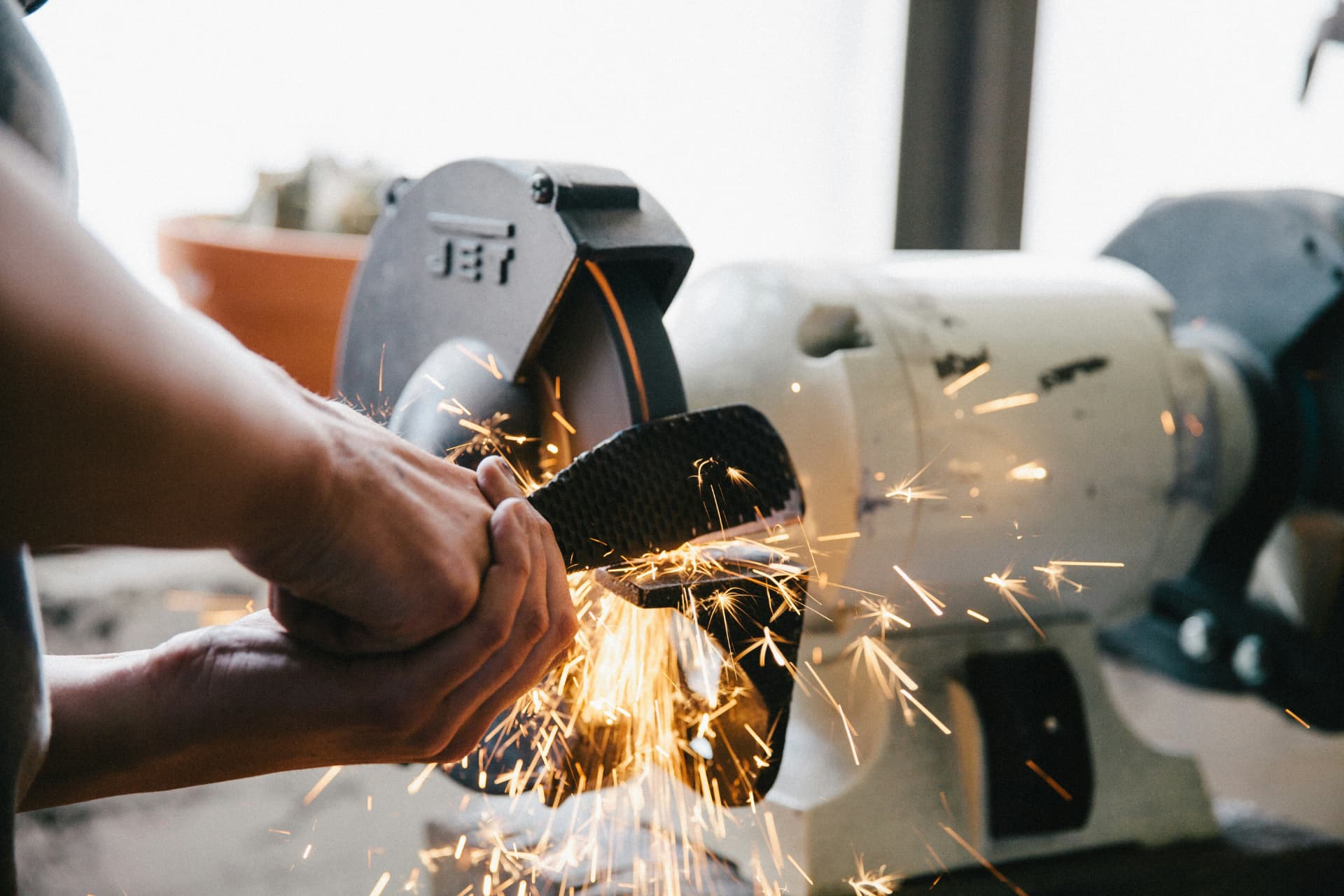 Operator grinding a cast buckle component with sparks flying
