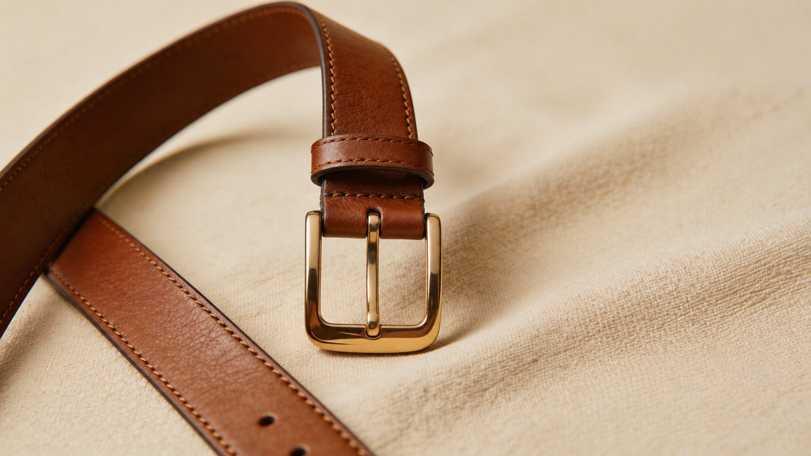 Polished gold roller buckle on a tan leather belt