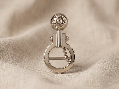 Ornate polished nickel scroll hook on linen