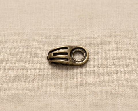 Antique brass vented cord slide fitting on linen